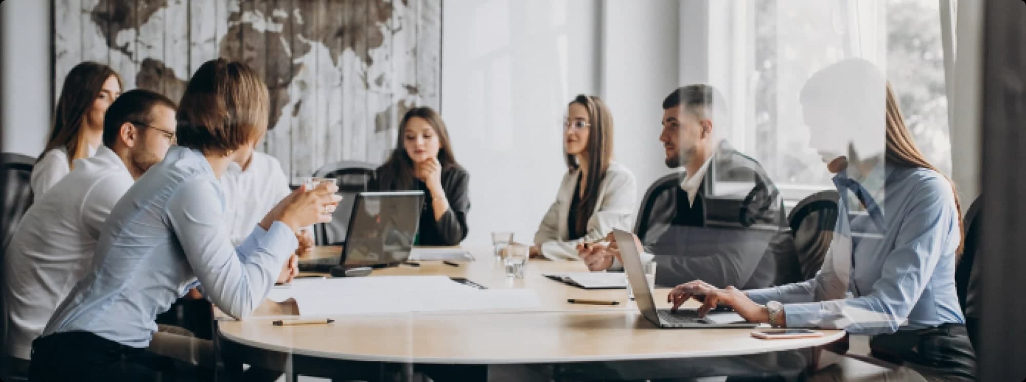 Equipe reunida ao redor de uma mesa, numa sala de reunião com luz natural