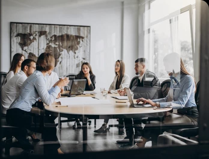 Team in a meeting in a room with a world map on the wall